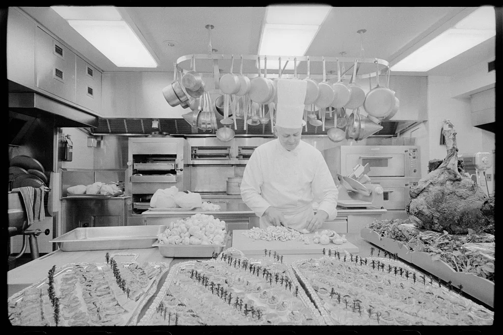 A chef chops mushrooms at a long counter in the White House kitchen in 1975
