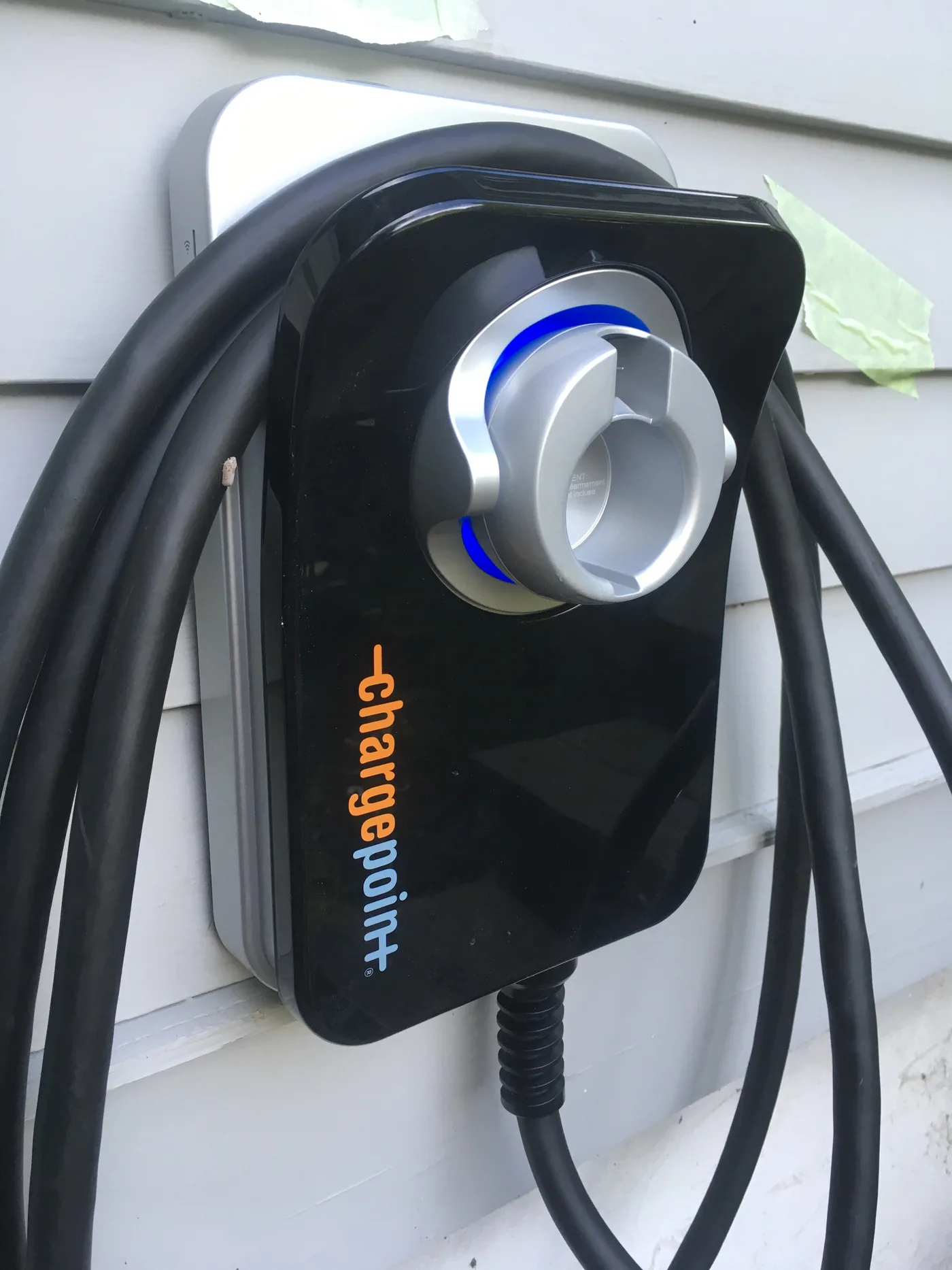 Black wall-mounted electric vehicle charger with its thick cable coiled around the unit