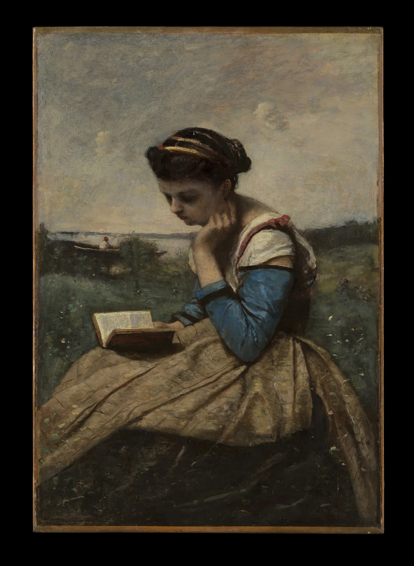A seated woman in a pale dress studies a book held close to her face in a quiet landscape