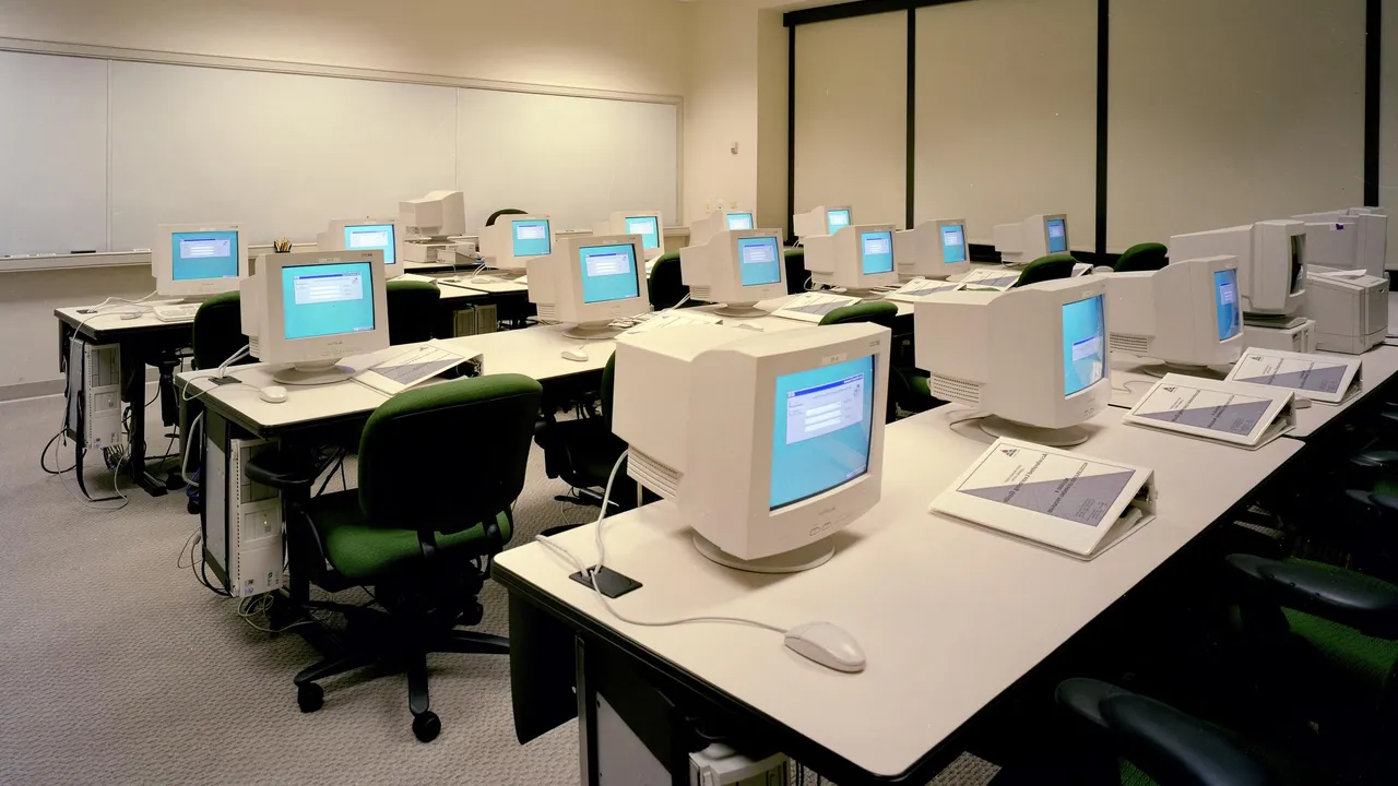 Rows of desktop computers and monitors arranged for a training session in a quiet technology classroom