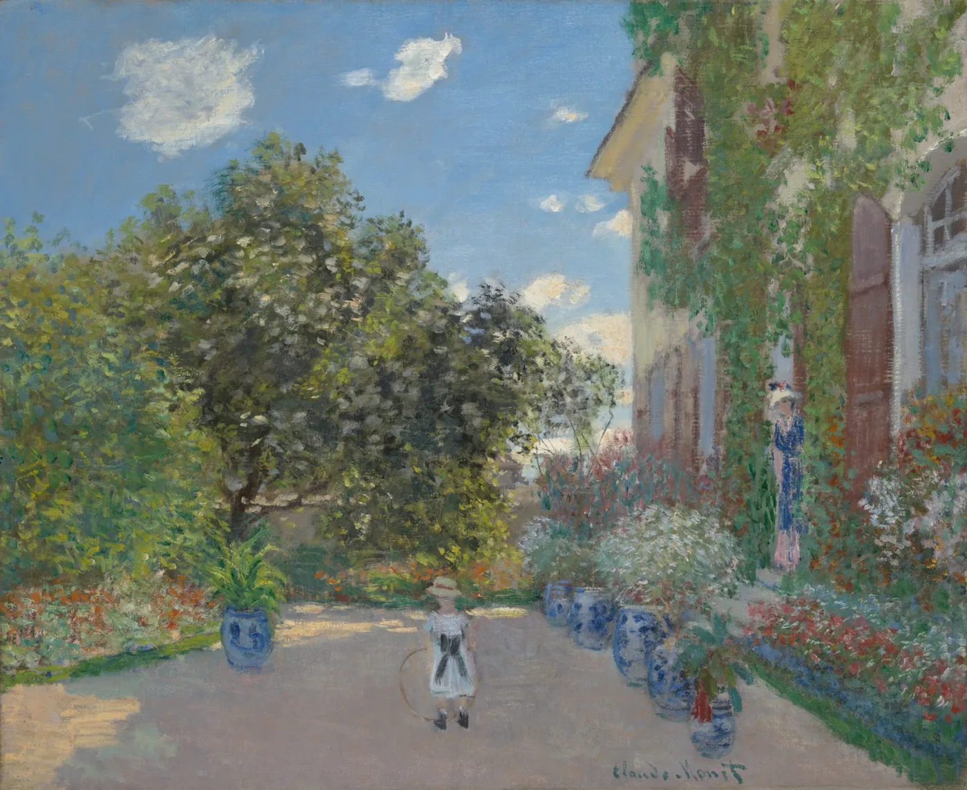 Sunlit garden path lined with blue-and-white planters before an ivy-covered house, a child with a hoop and a woman standing in the doorway