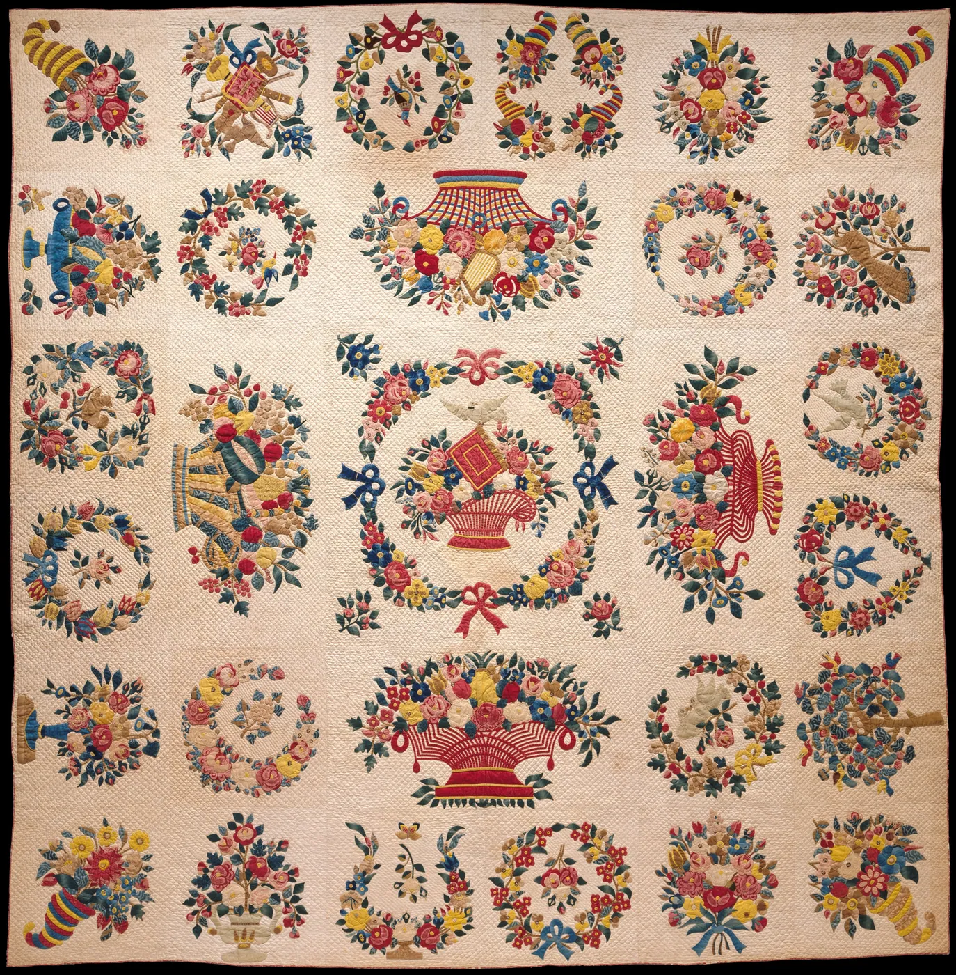 An appliqued album quilt of floral wreaths, baskets and cornucopias in red, blue, green and yellow on a finely quilted white ground.