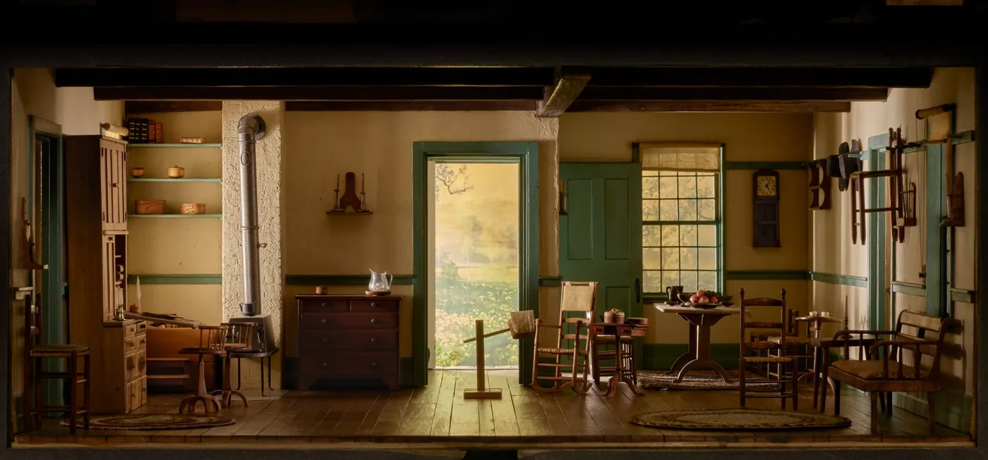 Miniature model of a spare Shaker living room with chairs hung on peg rails, a chest of drawers, a rocking chair and an open door to a garden