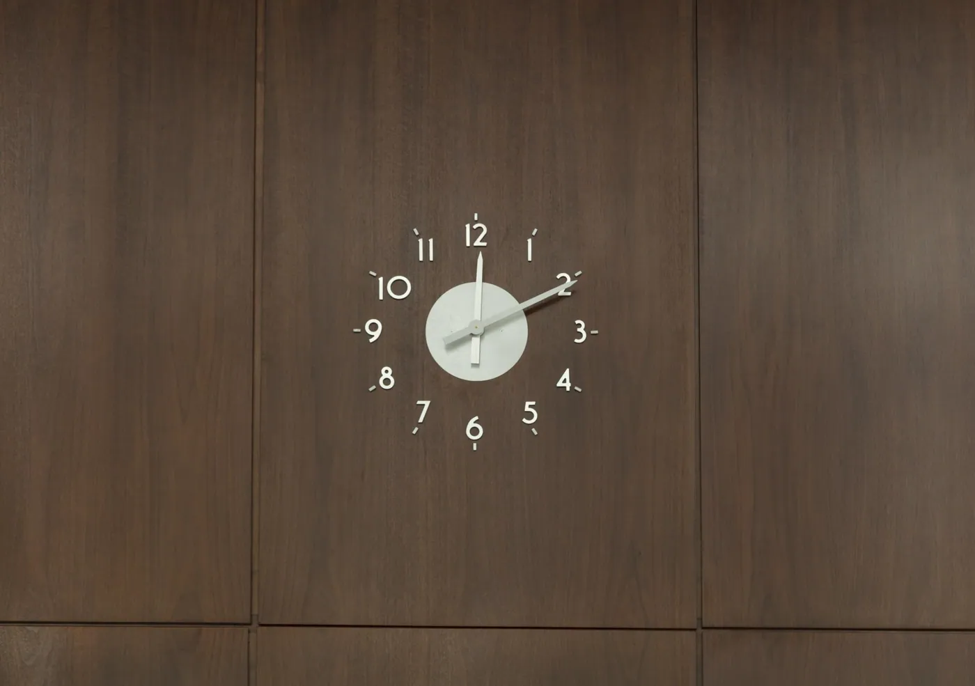 Minimal white clock with separate numerals mounted on dark rosewood wall panels in the lobby of Mies van der Rohe's Chicago Federal Center