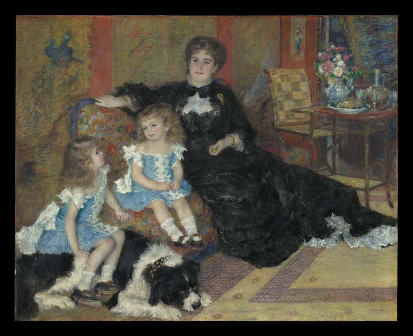 A mother in a black gown sits on a sofa beside her two small children in blue dresses, with a large black-and-white dog lying at their feet.