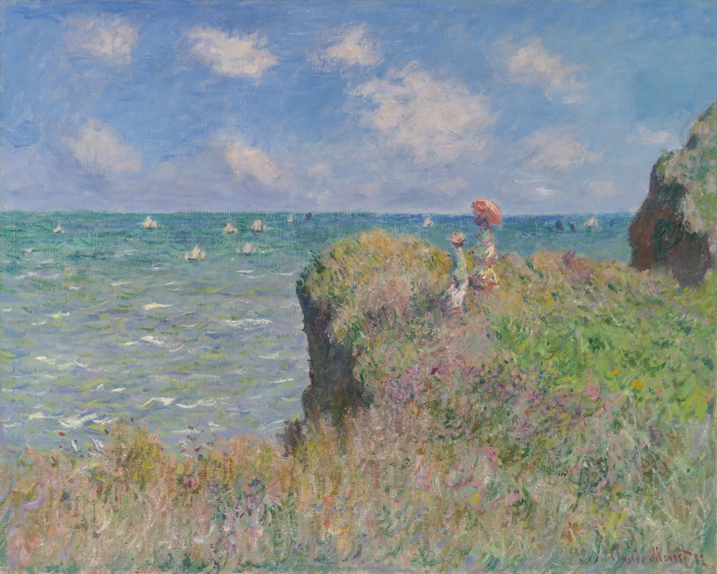 Two women, one holding a red parasol, stand on a grassy clifftop above a blue-green sea dotted with sailboats.
