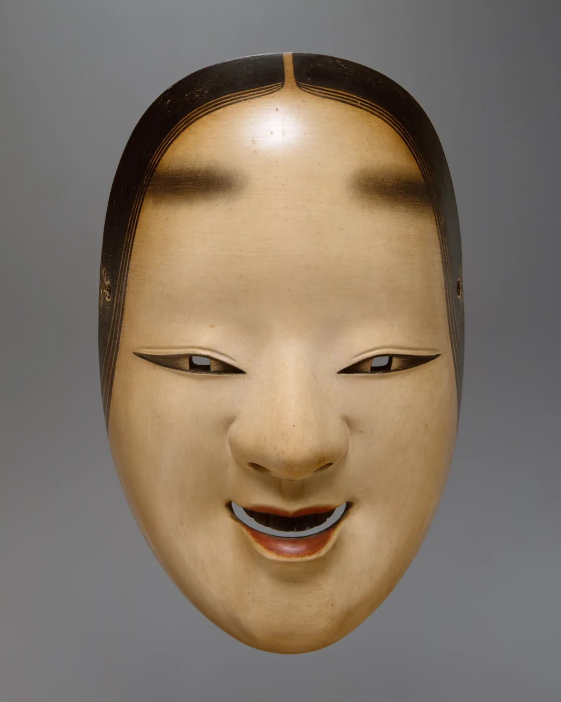 Carved and painted wooden Noh mask of a young woman's serene face, with painted brows, fine black hairlines, and parted red lips, on a grey ground