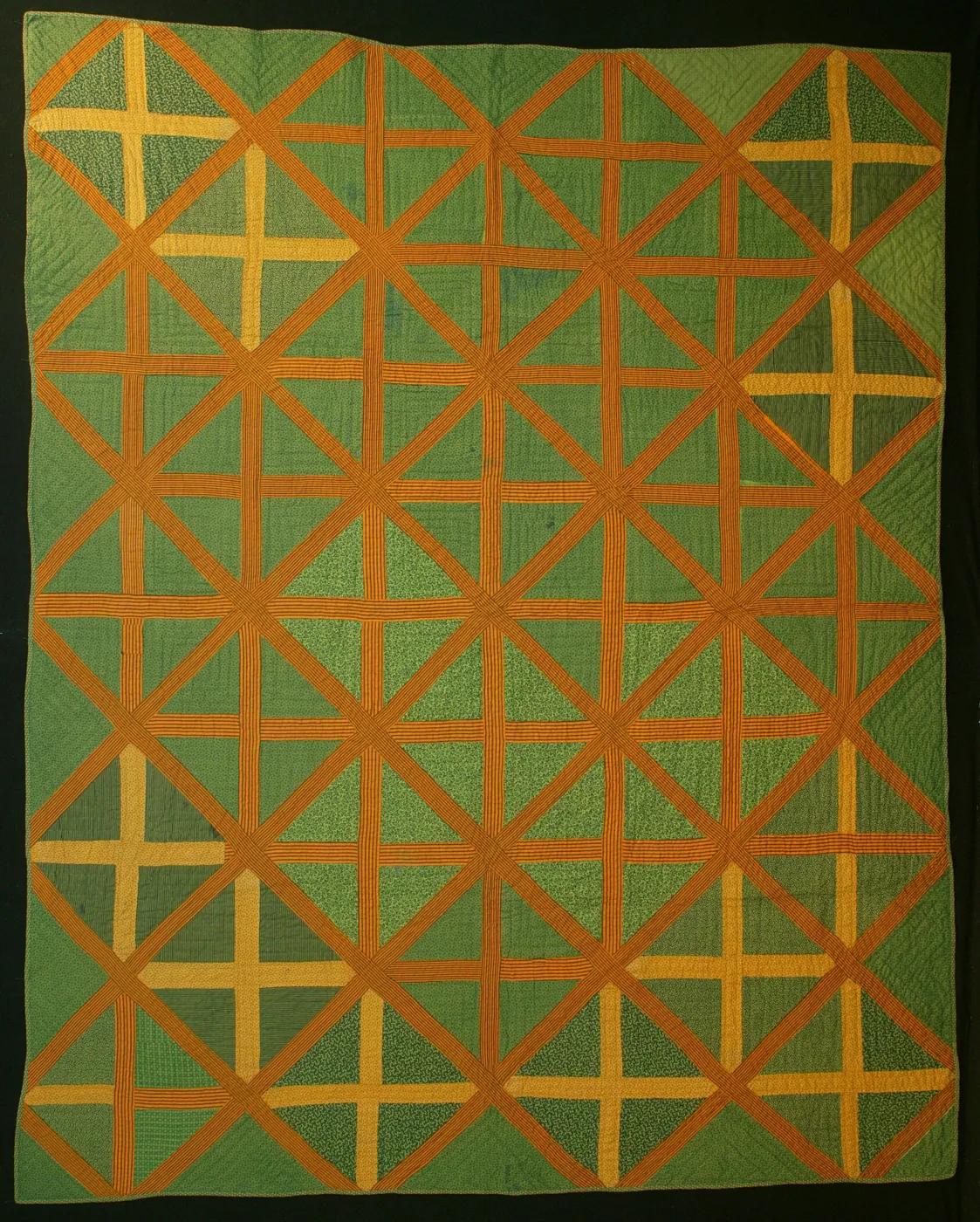 Nineteenth-century American quilt in green and burnt orange, pieced in a lattice of crossing diagonal and straight bands with yellow crosses