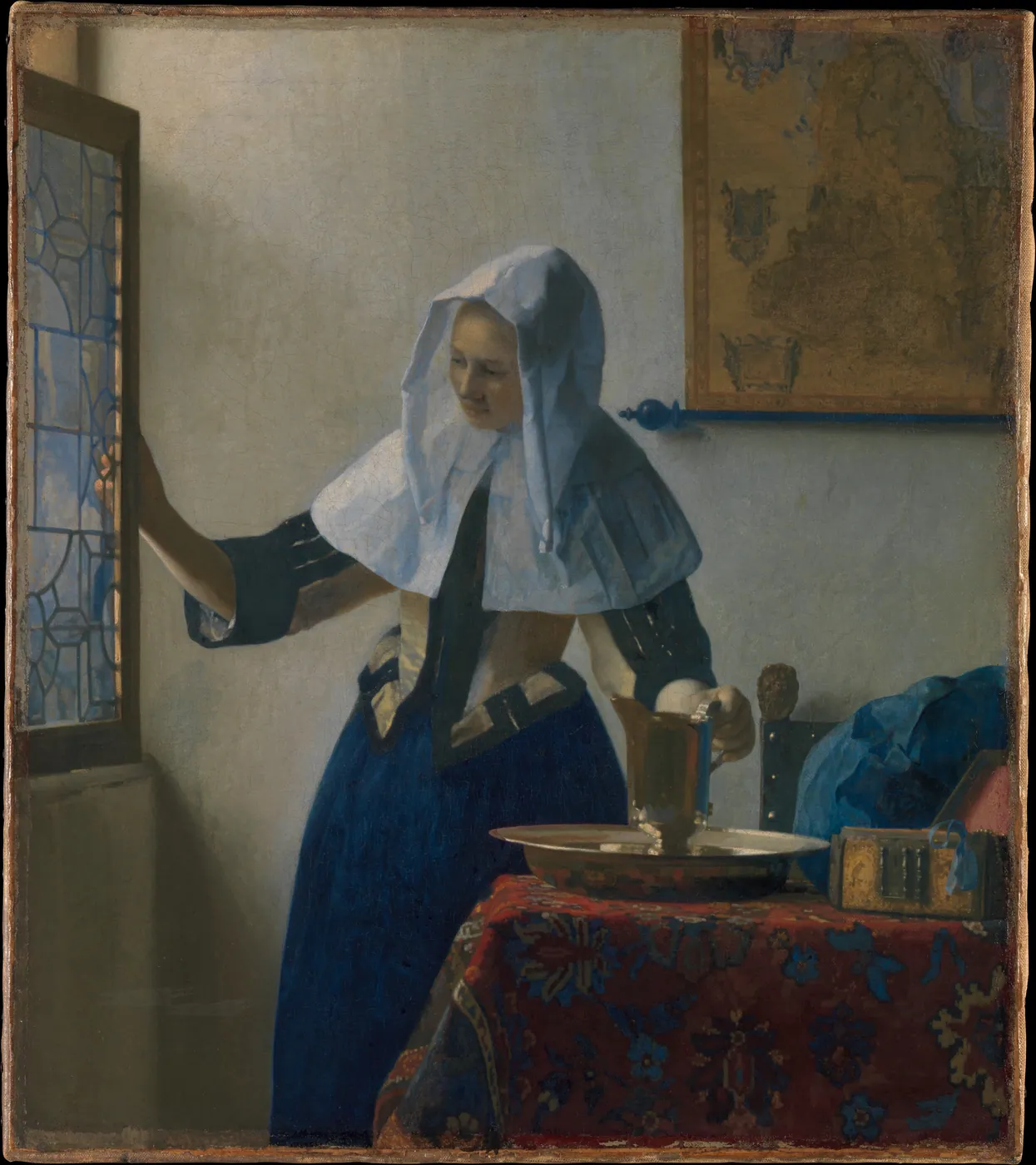 A woman in a white linen headcloth opens a leaded window with one hand and rests the other on a brass pitcher on a rug-covered table; a map hangs on the wall.
