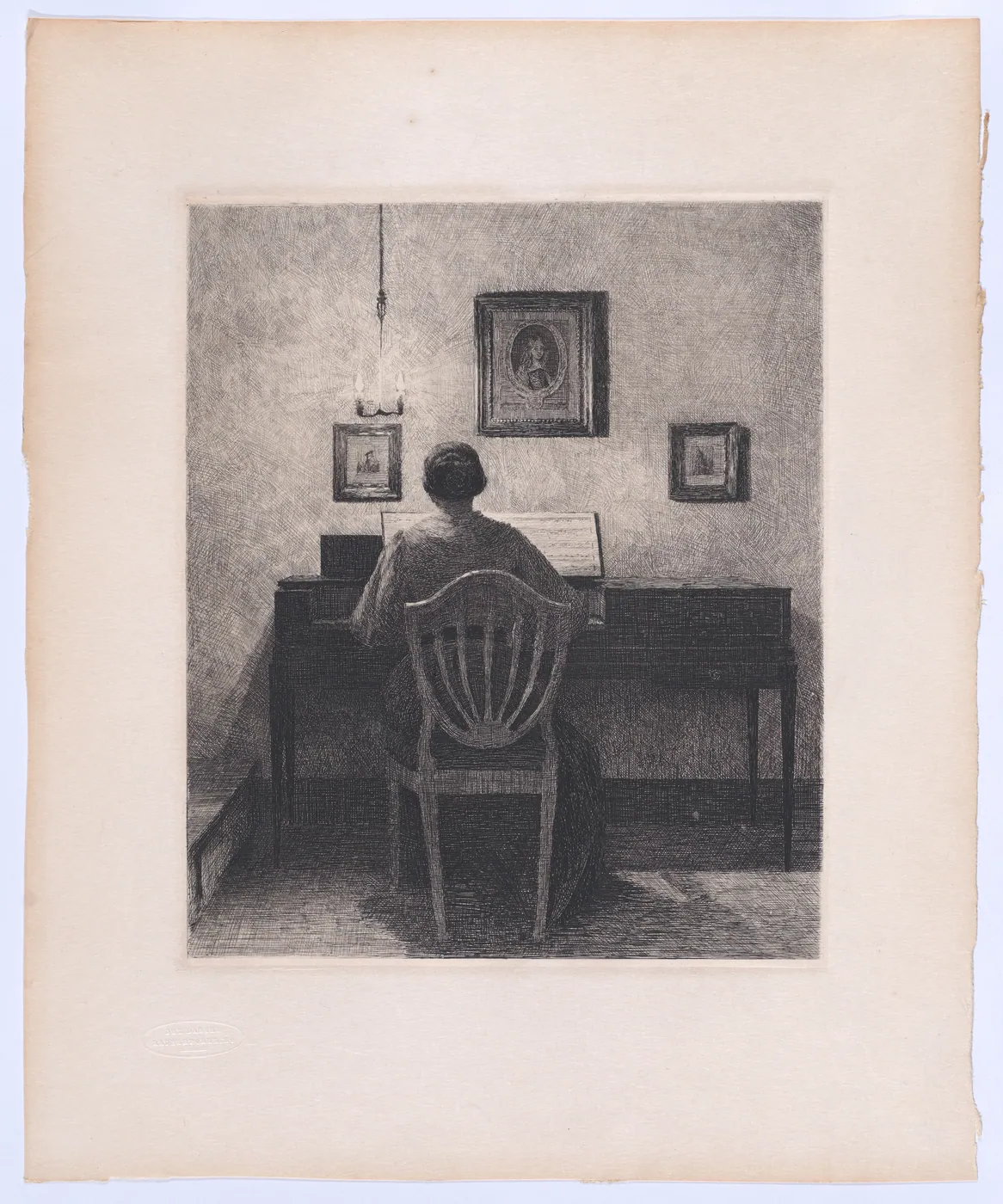 An etching of a woman seen from behind, seated at an upright piano in a lamplit room hung with framed pictures.