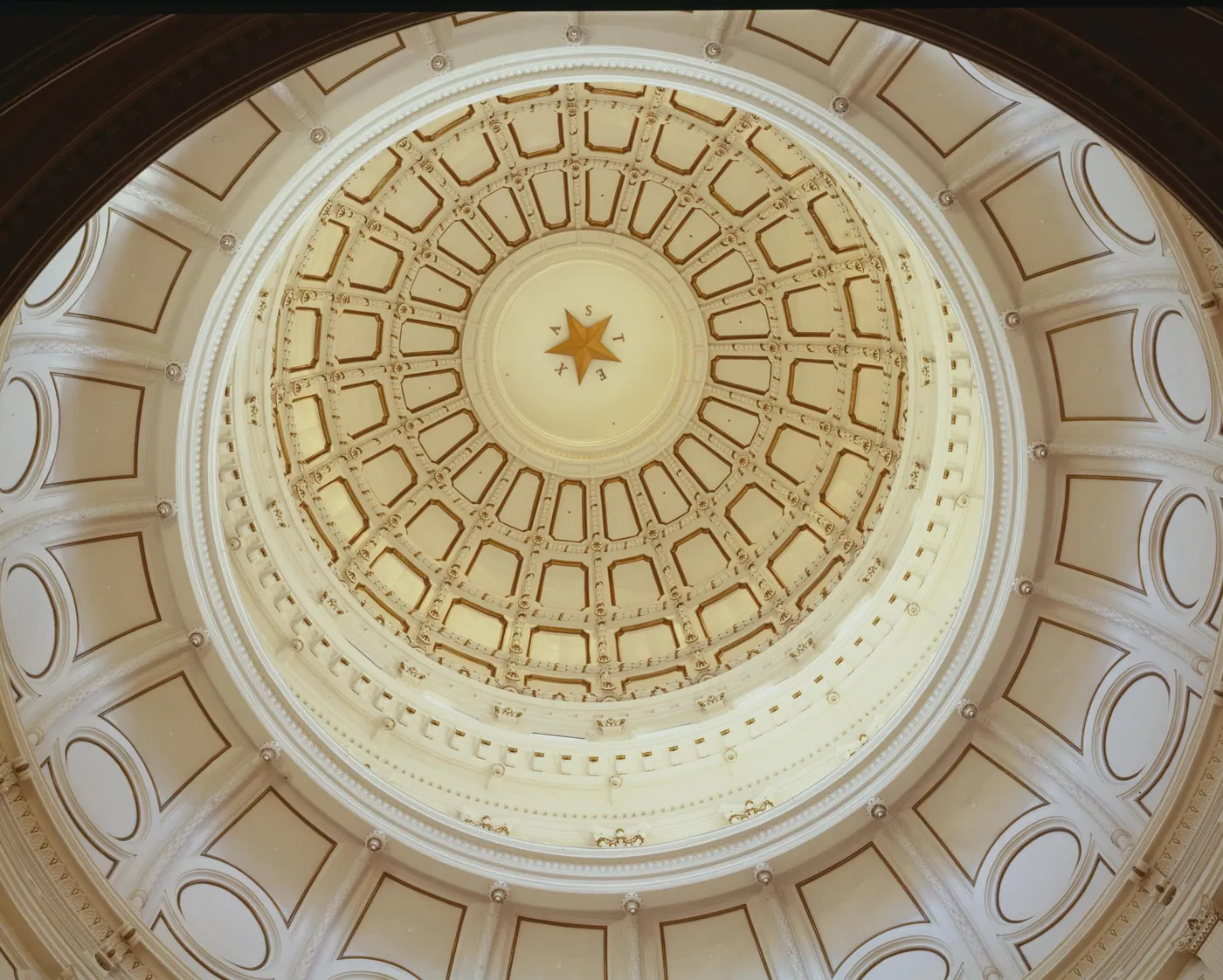 Looking up into the cream and gold coffered interior of the Texas Capitol dome, with a single gold star at its centre