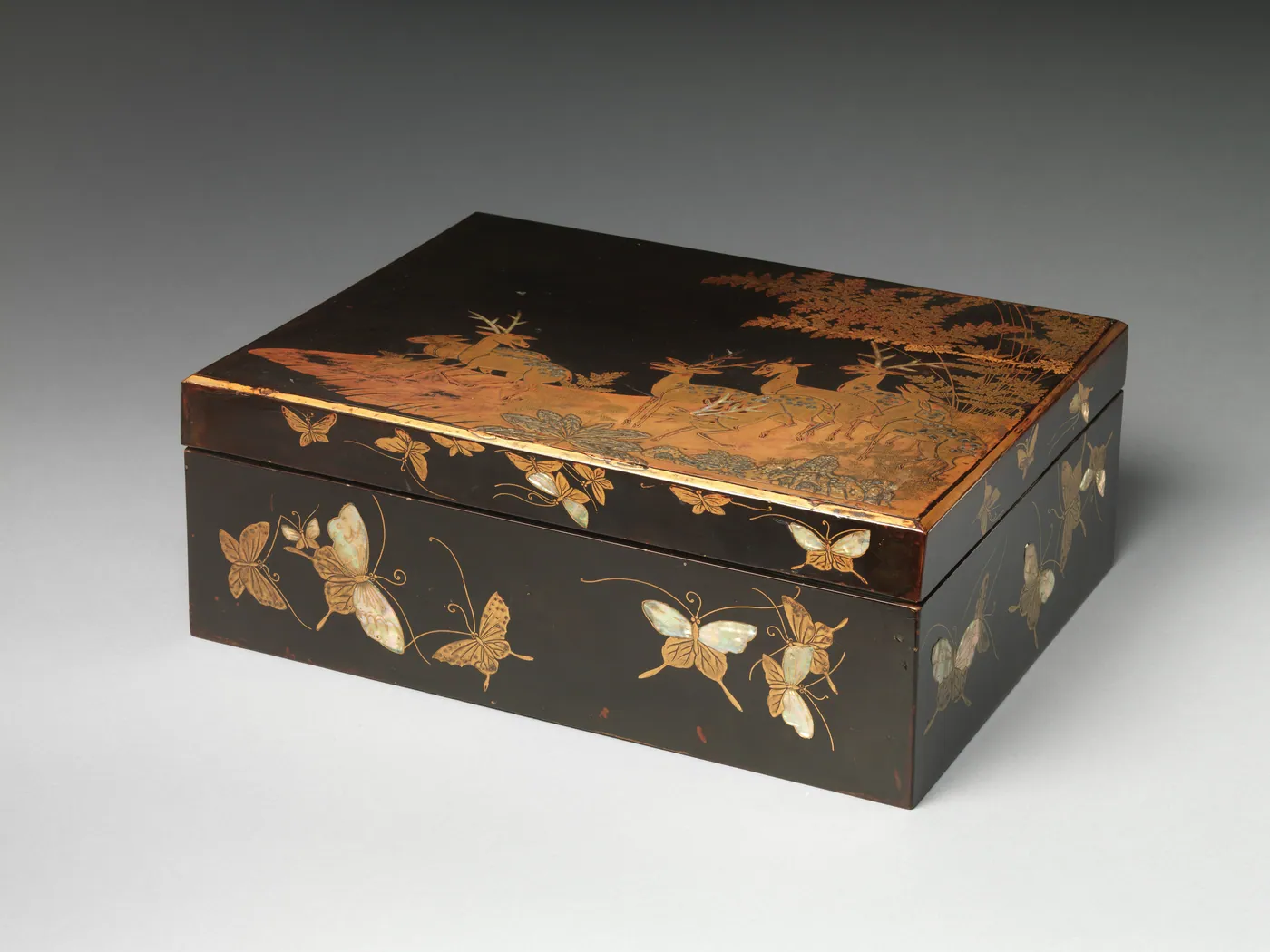 Black lacquer document box with gold deer and ferns on the lid and inlaid mother-of-pearl butterflies around its sides.