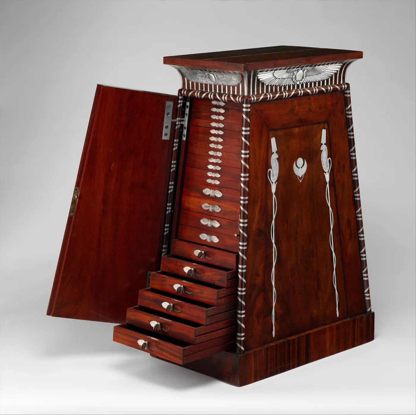 Tapered mahogany coin cabinet with silver inlay, its side door open to show a tall stack of small drawers, several pulled out