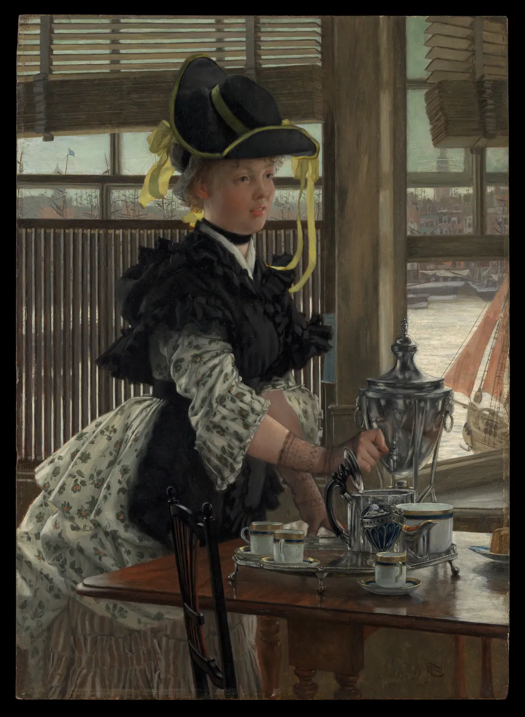 A woman in a black hat with yellow ribbons pours from a silver samovar into cups on a wooden table by a window overlooking a harbour