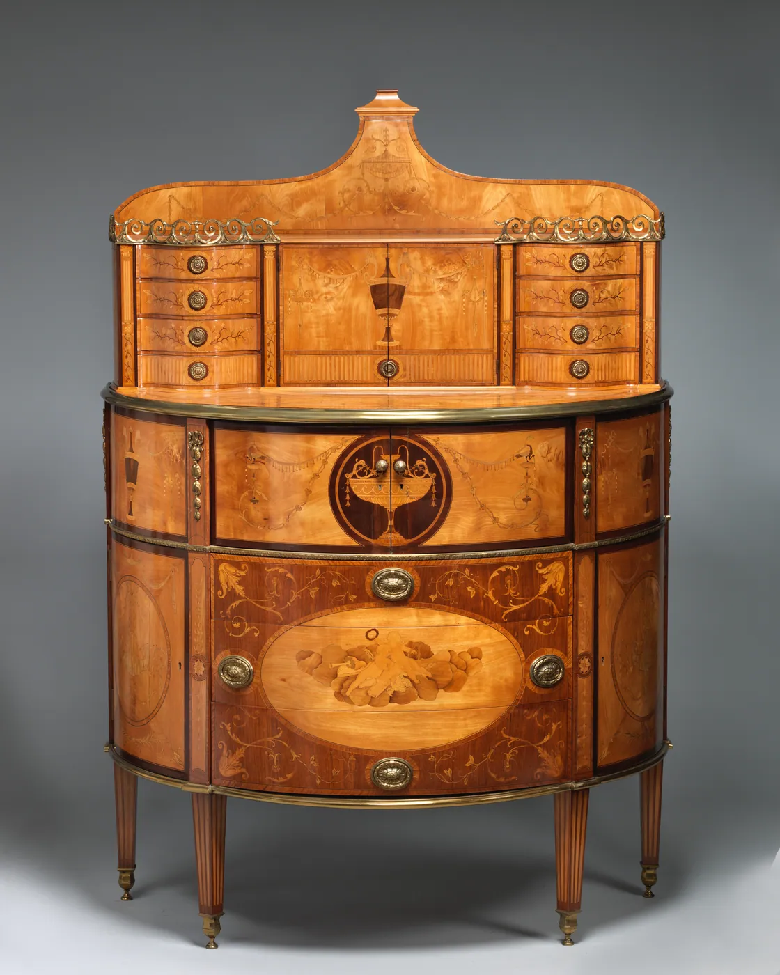Demilune satinwood secretary desk with fine marquetry inlay, a superstructure of small brass-knobbed drawers and a central cupboard, on tapered legs