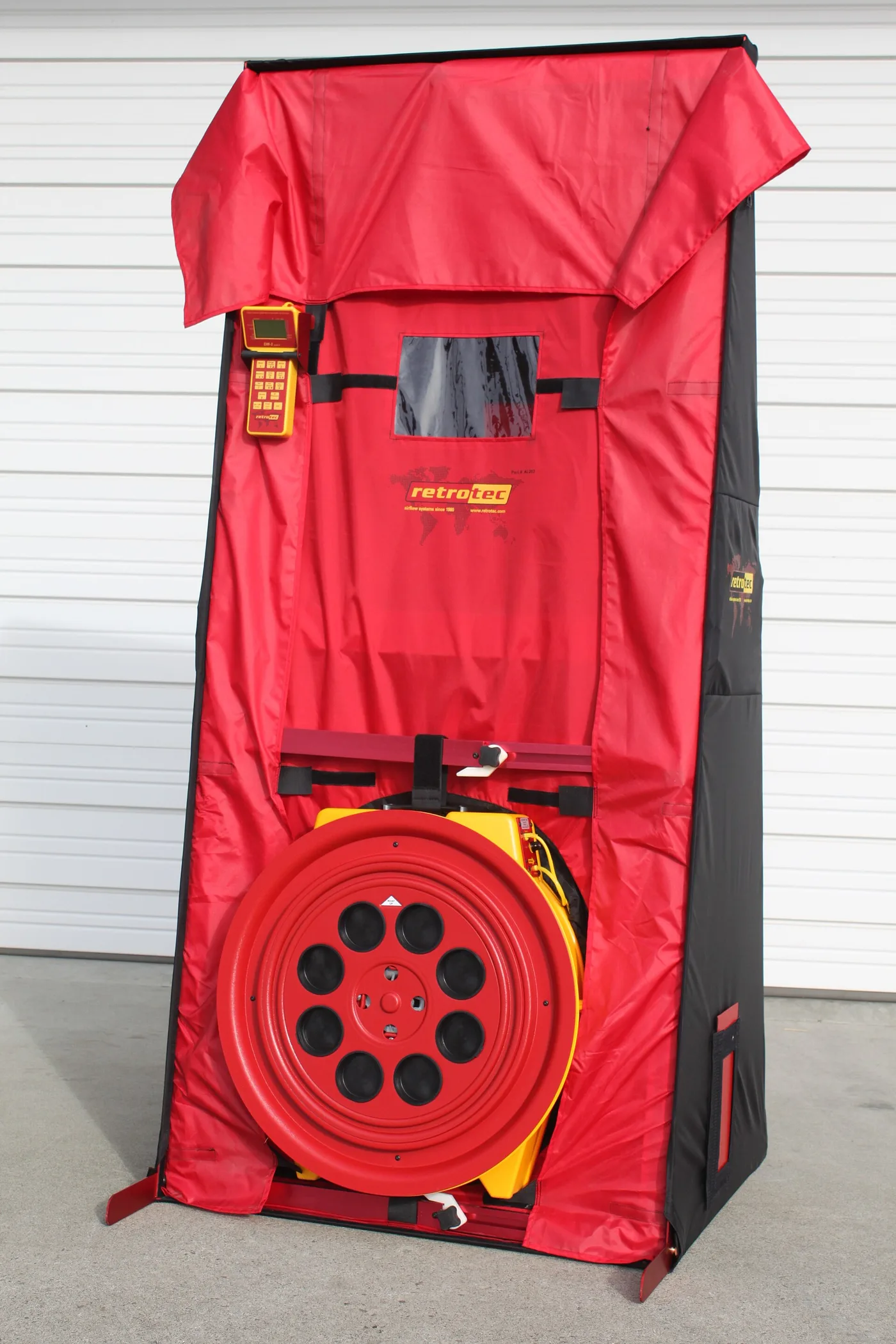 Red blower-door testing frame with a large calibrated fan and digital pressure gauge