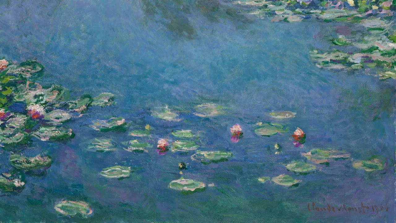 Pink water lilies and green pads floating on a still pond that reflects blue sky and soft clouds